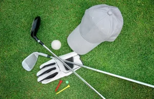 越南高尔夫行李清单封面：球杆、手套与鸭舌帽摆放在草坪上，呼应去越南打球的必备物品指南