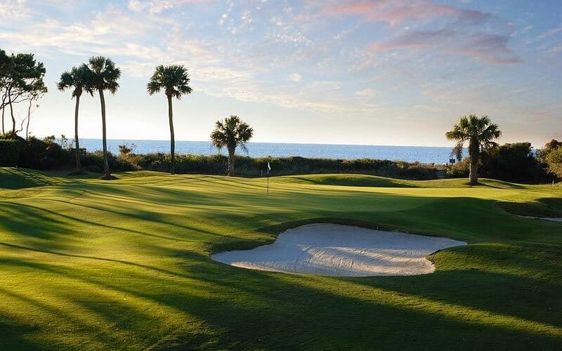 Beautiful golf course in Da Nang with palm trees and ocean view at sunset