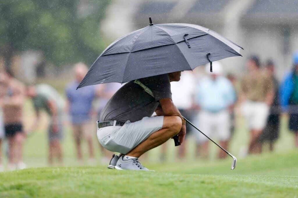 Golf in Da Nang rainy season – golfer with umbrella on wet fairway