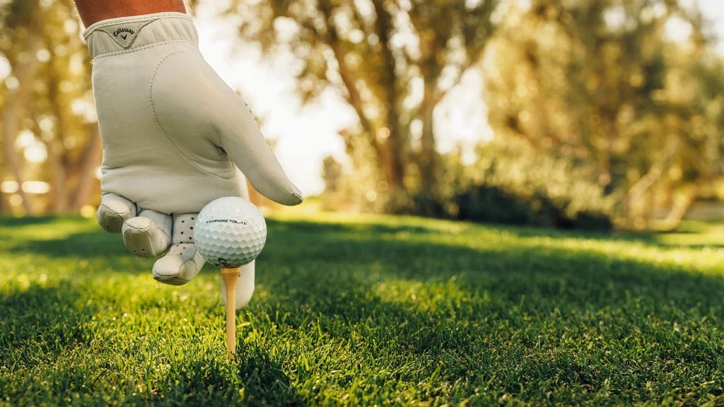 Beginner golfer placing golf ball on tee before hitting a shot on a golf course