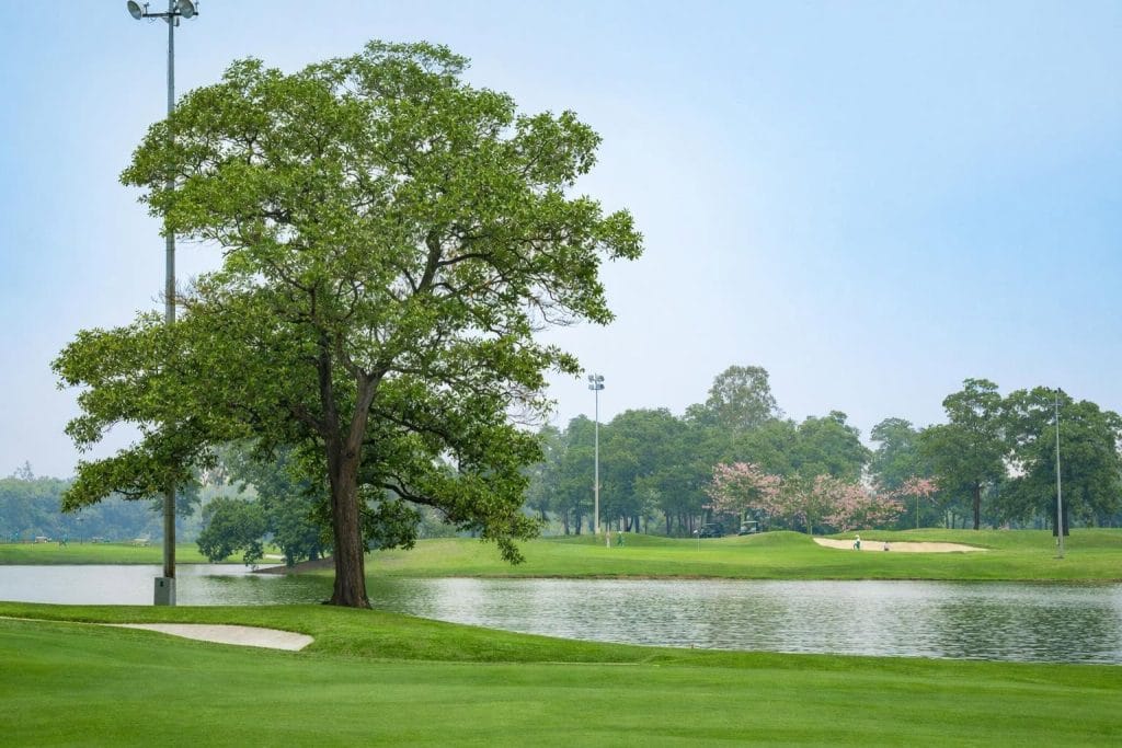 Lakeside golf hole near Hanoi with floodlight towers beside the fairway