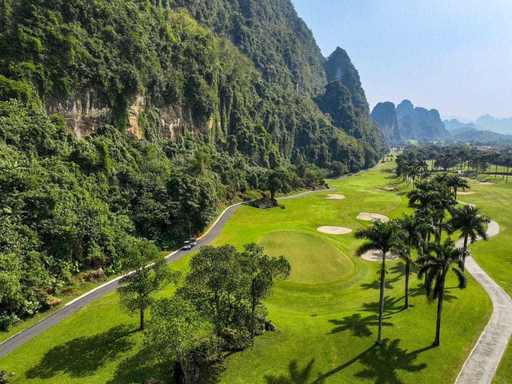 Phoenix Golf Resort fairway running beside dramatic limestone cliffs, lined with palm trees