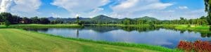 Panoramic view of Dai Lai Star Golf & Country Club fairway beside Dai Lai Lake, with forested hills reflected in the water