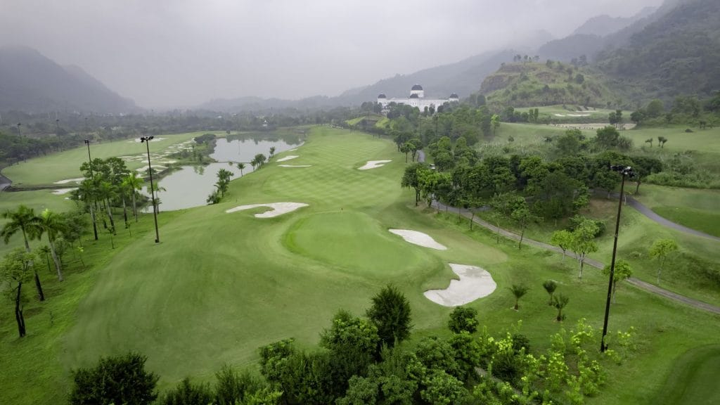 Aerial view of Stone Valley Golf Resort fairway and bunkers, with the clubhouse and misty mountains in the background
