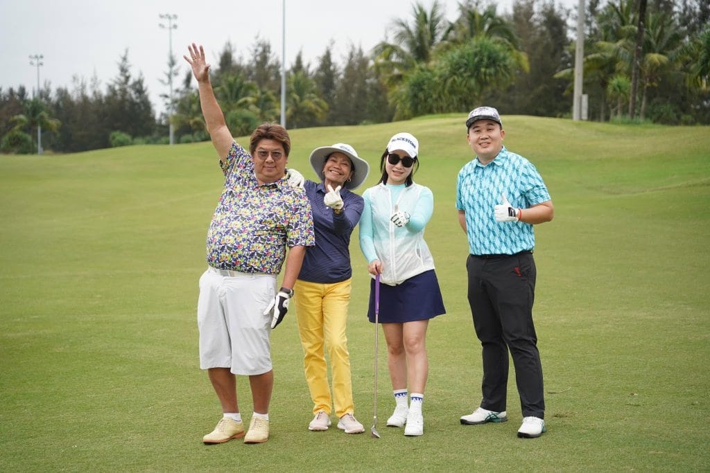 Group of four Asian golfers celebrating on the fairway during a Da Nang golf trip, the kind of long-weekend group booking Filipino golfers make