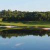 BRG Legend Hill Golf Resort green surrounded by sweeping sand bunkers, with a still lake reflecting the fairway at golden hour