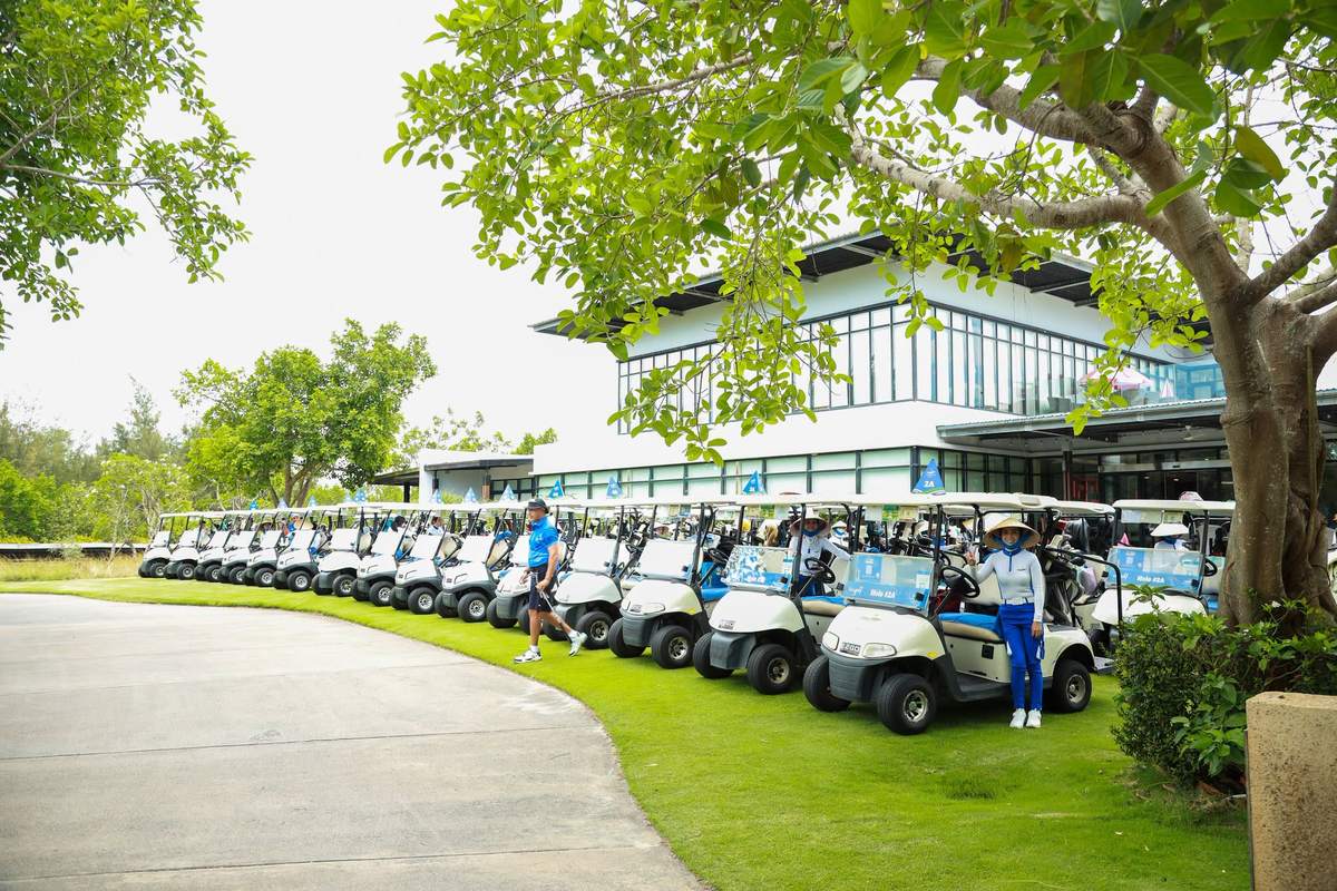 Rows of golf buggies lined up outside a Da Nang clubhouse for a shotgun start, each marked with a starting hole — peak season dates fill the whole course at once