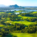 Aerial view of a Hanoi golf course with fairways, lakes and limestone hills behind