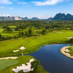 Aerial view of Sky Lake Resort & Golf Club fairways winding around a lake, with limestone karst mountains in the background