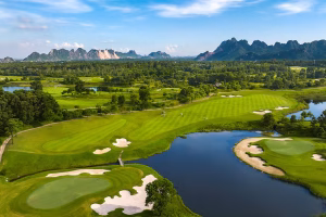 Aerial view of Sky Lake Resort & Golf Club fairways winding around a lake, with limestone karst mountains in the background