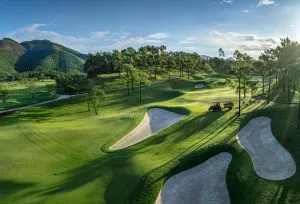 Silk Path Dong Trieu Golf and Country Club fairway with bunkers and forested hills