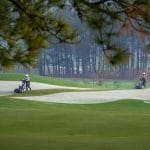 Golfers on a Silk Path Dong Trieu green lined with mature pine trees