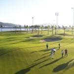 Golfers walking a Tuan Chau Golf Resort fairway beside the sea