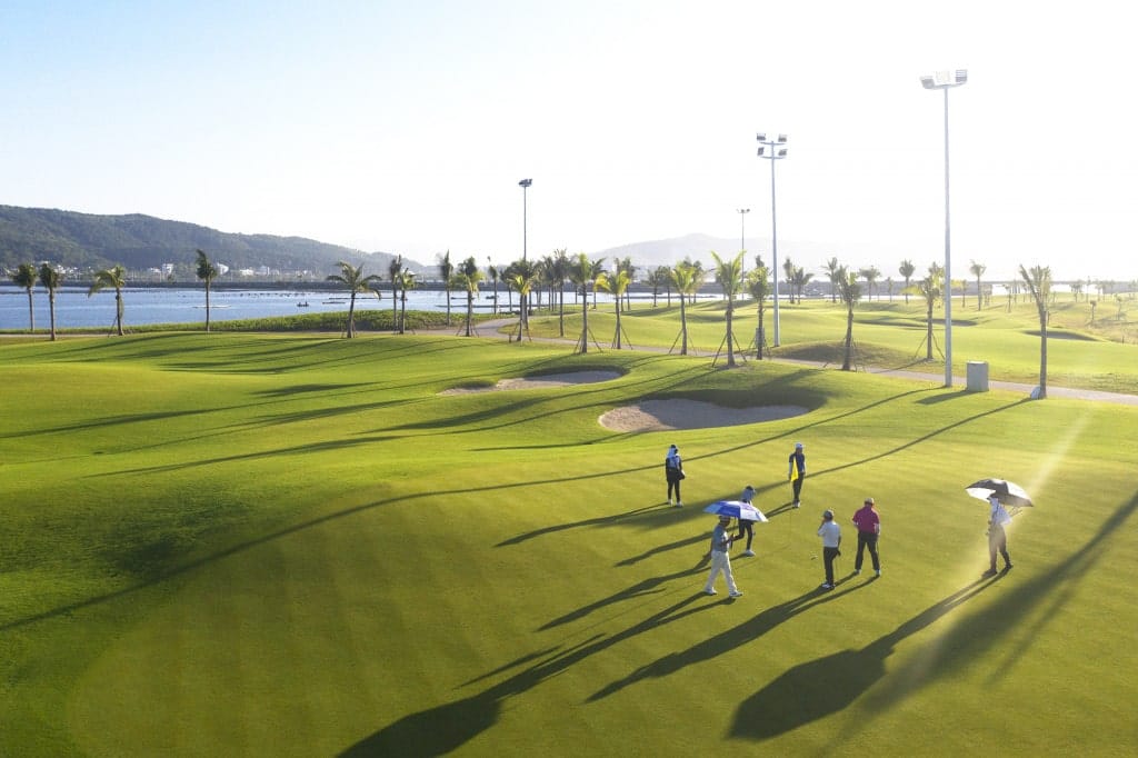 Golfers walking a Tuan Chau Golf Resort fairway beside the sea
