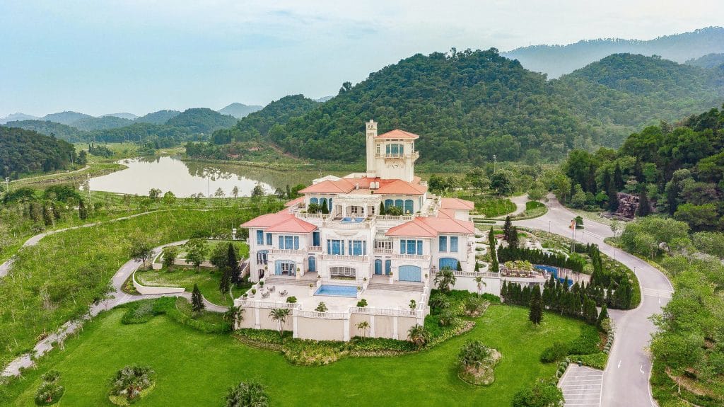 Aerial view of BRG Legend Hill Golf Resort clubhouse mansion surrounded by mountains near Hanoi