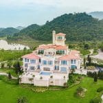 Aerial view of BRG Legend Hill Golf Resort clubhouse mansion surrounded by mountains near Hanoi