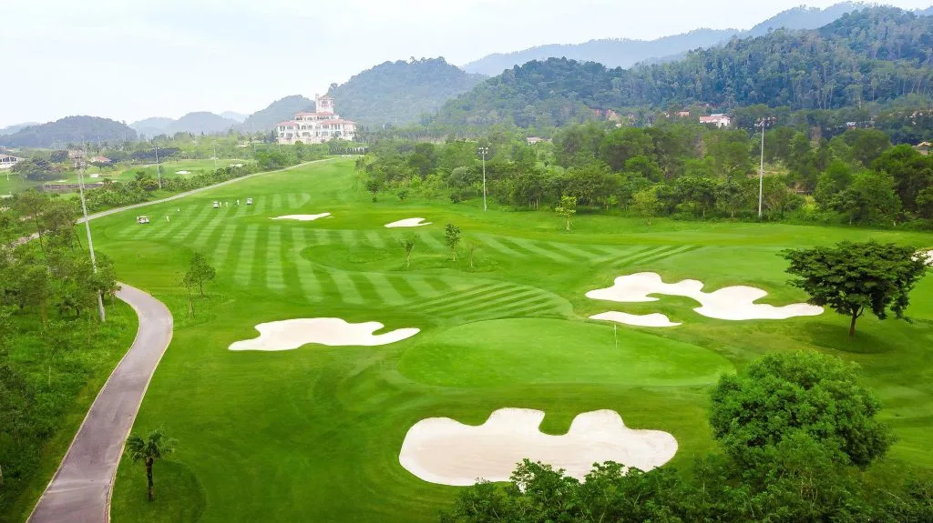 Island green with stone bridge at BRG Legend Hill Golf Resort, clubhouse in the background