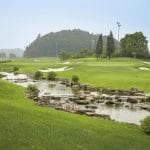 BRG Legend Hill Golf Resort green ringed by white sand bunkers with a stream at golden hour