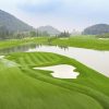 Lakeside fairway framed by white sand bunkers and low hills at BRG Legend Hill Golf Resort, Hanoi