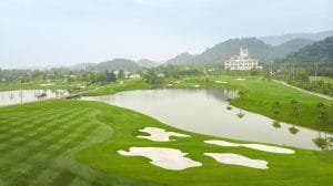 BRG Legend Hill Golf Resort fairway with white bunkers, a lake and the hilltop clubhouse in Soc Son near Noi Bai Airport