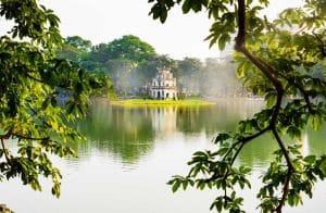 Turtle Tower on Hoan Kiem Lake framed by trees, a morning walk for non-golfers in Hanoi