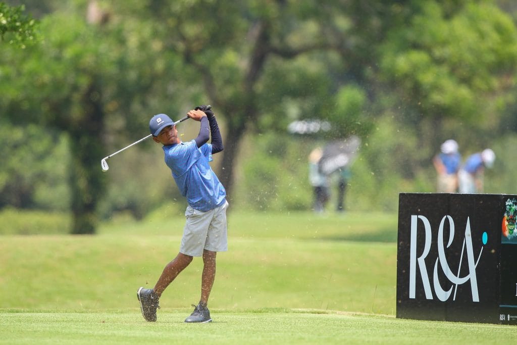 Junior golfer following through on an iron shot from the fairway at a youth golf tournament