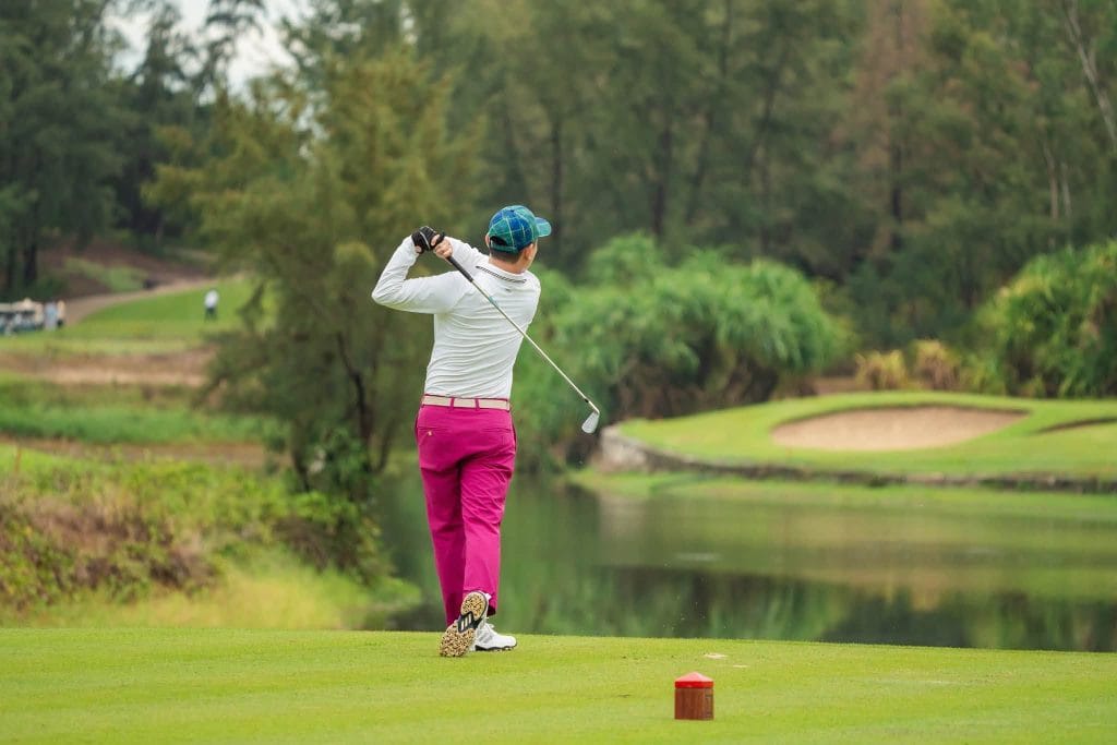 Solo golfer alone on the tee after hitting a drive over water on a Vietnam golf course