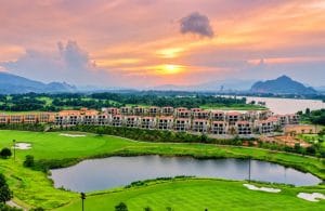 Golf resort villas beside a lake and fairway at sunset, a stay-and-play option near Hanoi