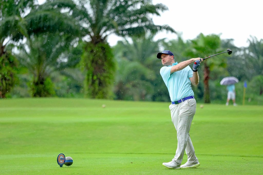 Golfer teeing off on a palm-lined fairway near Ho Chi Minh City, a popular golf trip from Australia