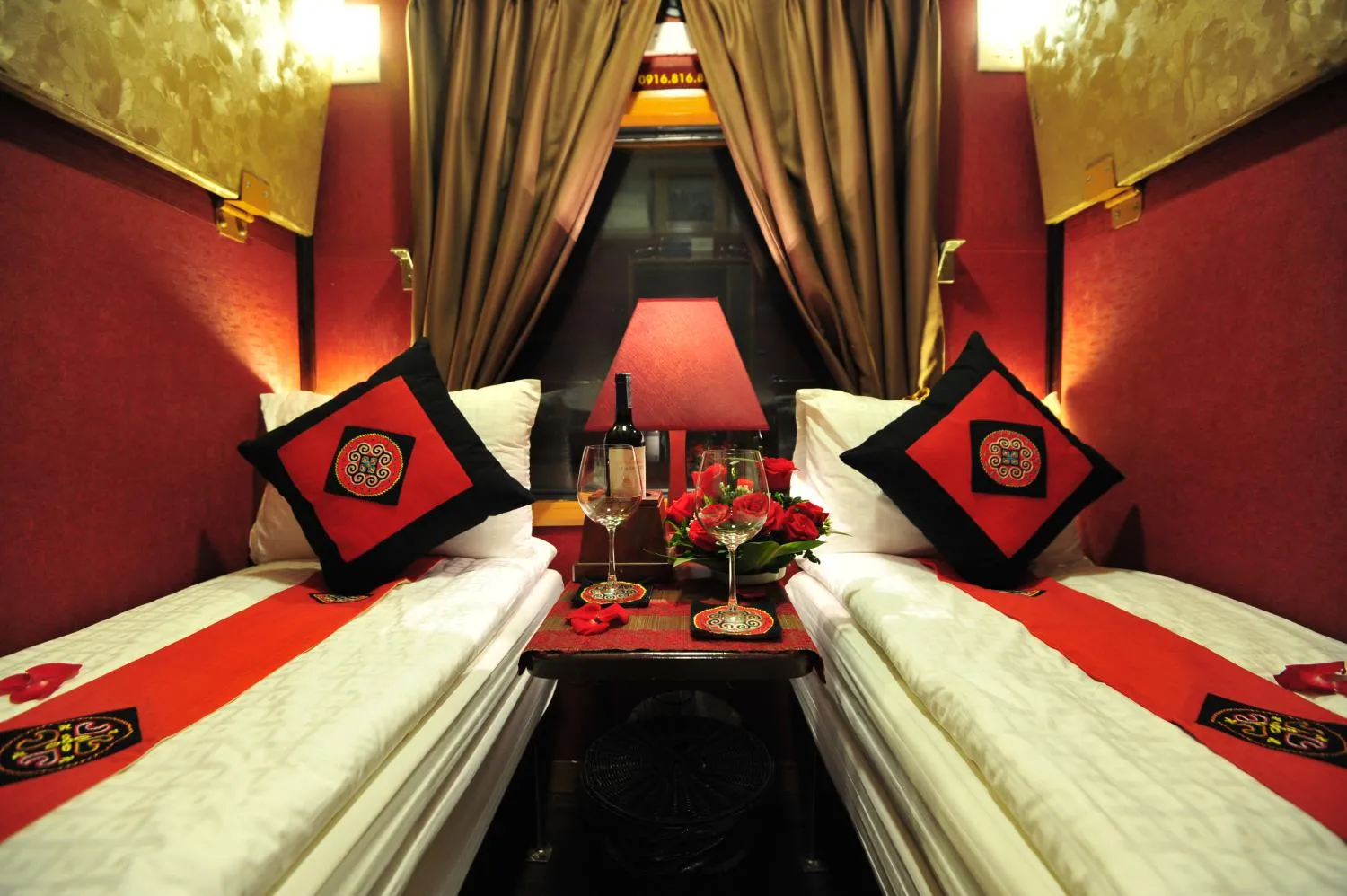 Two-berth private sleeper cabin with red and gold decor on the overnight train from Hanoi to Lao Cai