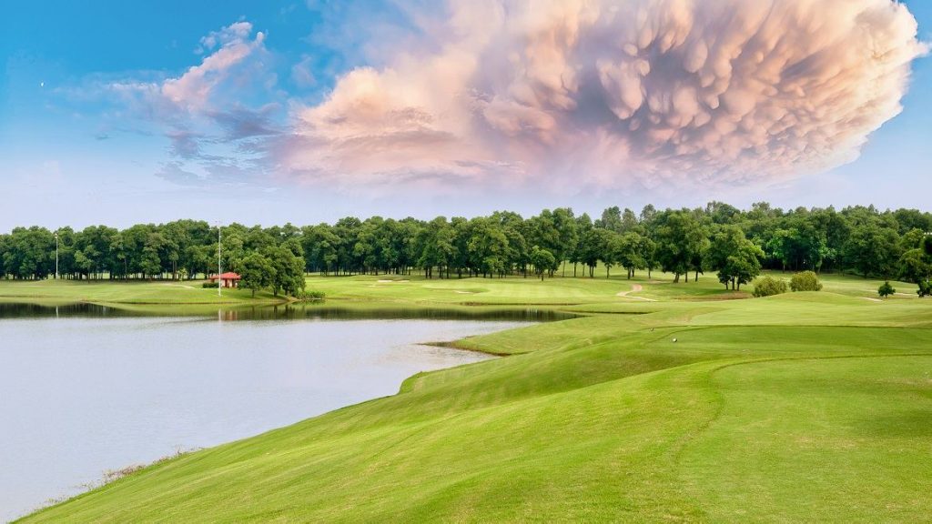 Lakeside fairway at BRG Kings Island Golf Resort near Hanoi, with a lake on the left and woodland behind