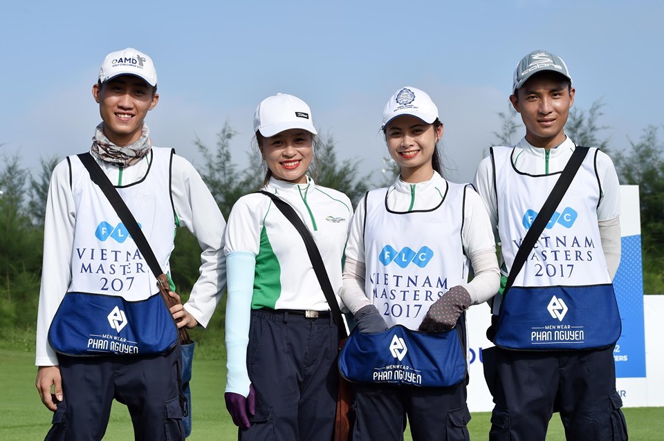 Caddies at a Vietnam golf tournament Four caddies in tournament bibs smiling on a golf course in Vietnam