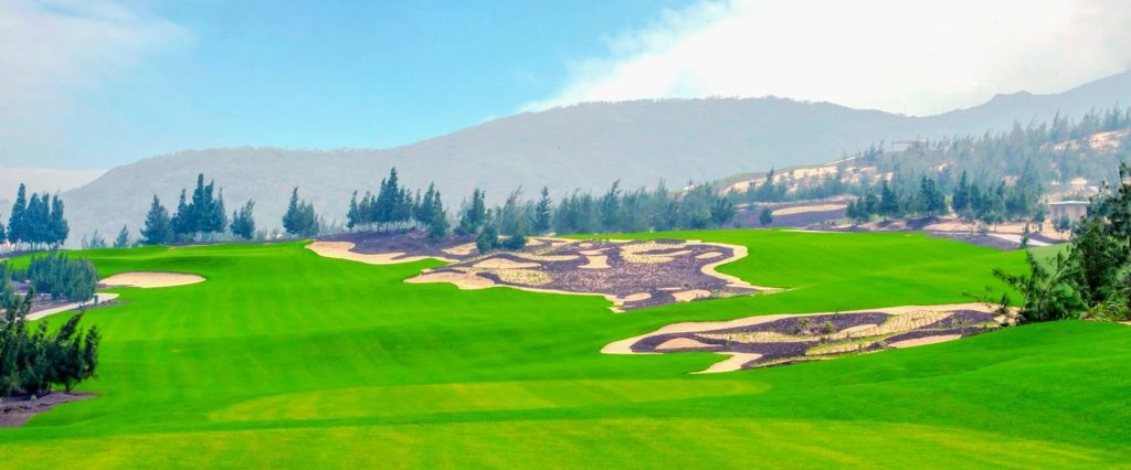 Wide fairway and bunkers on the FLC Quy Nhon Mountain Course with mountains in the distance
