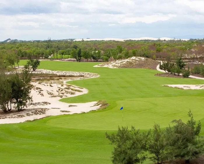 Green on the FLC Quy Nhon Mountain Course set against sand dunes and pine scrub