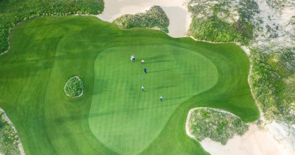 Aerial view of a green surrounded by sand on the FLC Quy Nhon Ocean Course