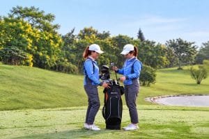 Two caddies sorting clubs in a golf bag on the tee before a round near Hanoi