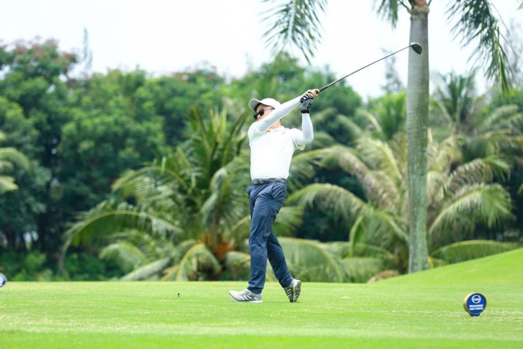 Golfer teeing off among palm trees in Ho Chi Minh City, a weekend golf trip from Singapore