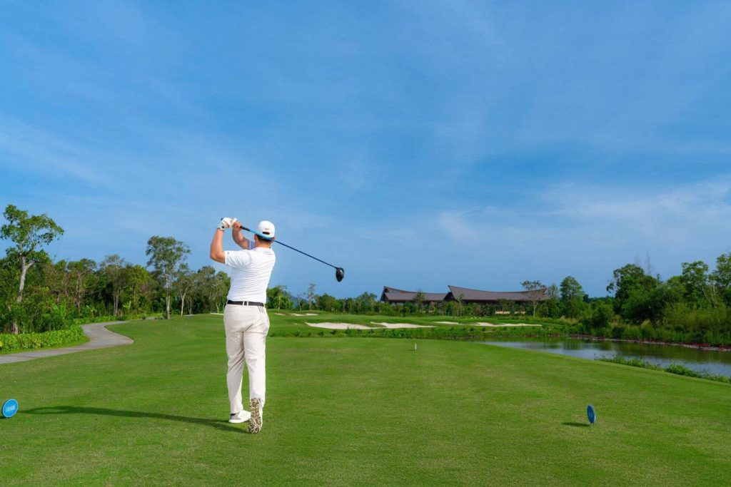 Golfer teeing off beside a lake on a Phu Quoc golf course, the kind of round a nonstop trip from Taiwan is built around