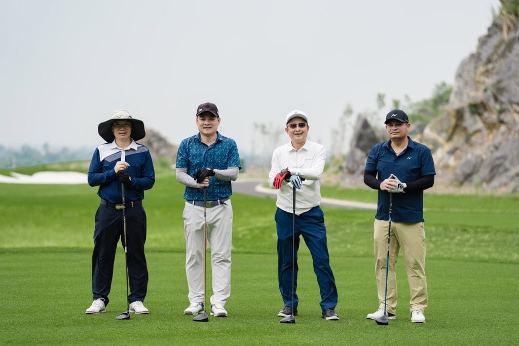 Four golfers standing on a fairway beside a limestone outcrop at a golf course near Hanoi