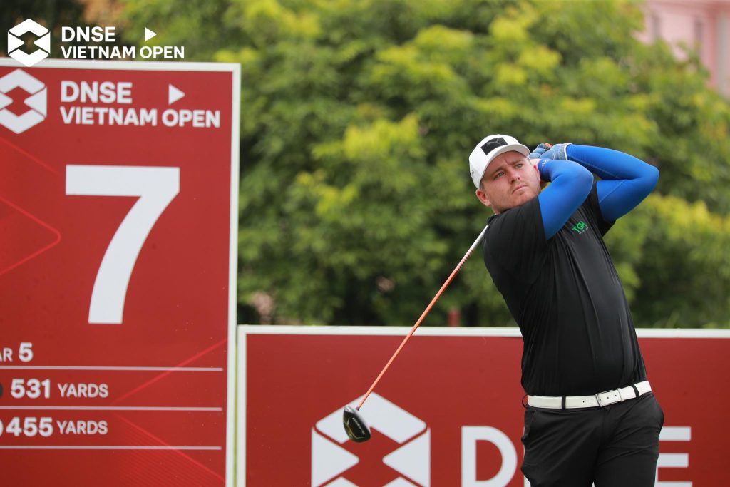 Golfer driving off the tee at a professional tournament in Vietnam, inspiration for a Hanoi golf trip from Australia